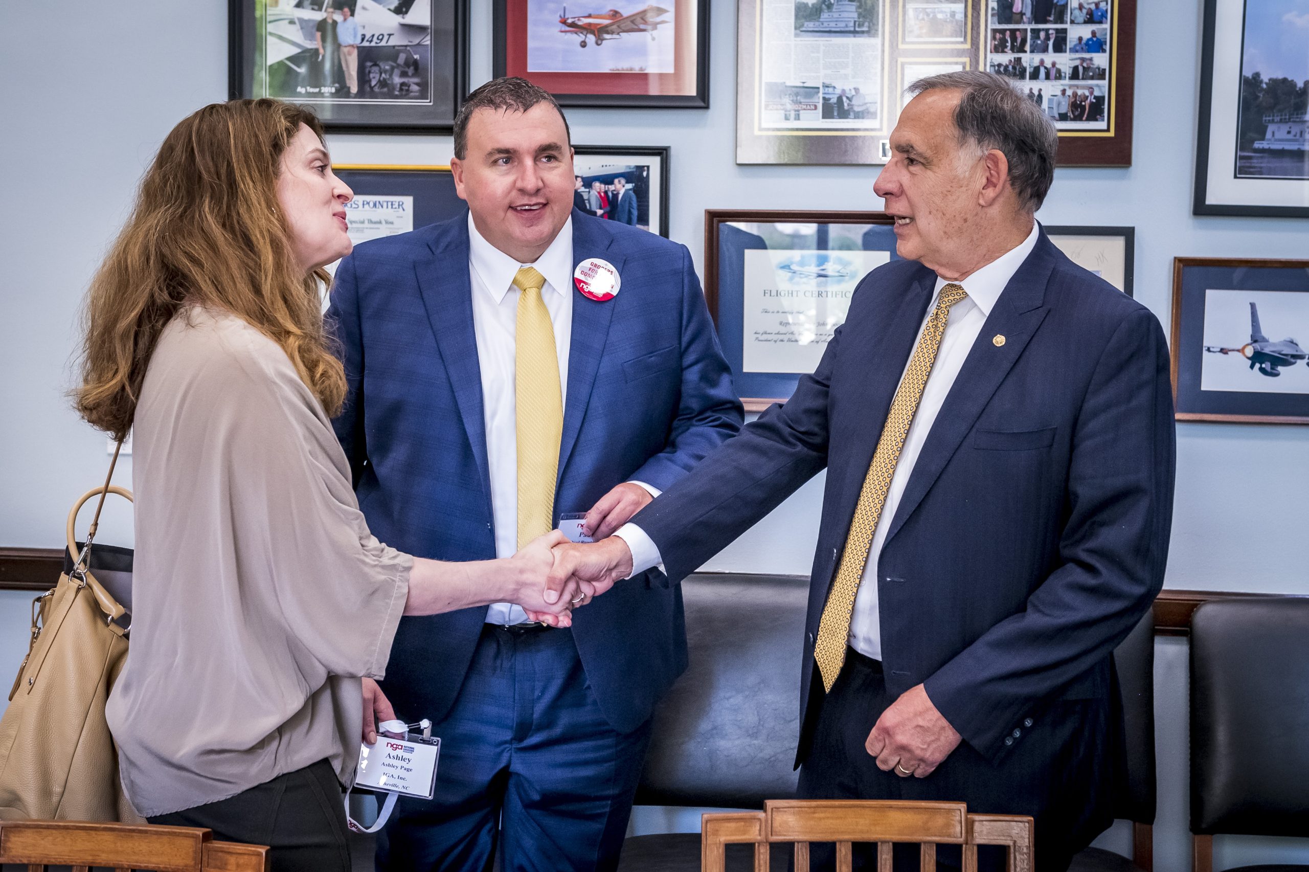 Two men and a woman shaking hands during a meeting in an office.