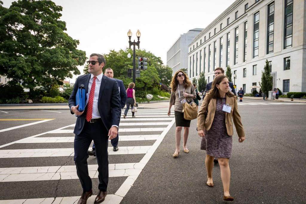 Group of people in business attire crossing a city street.