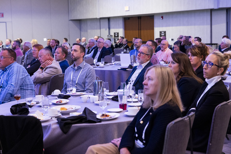 Audience seated at round tables listening during an NGA conference session.