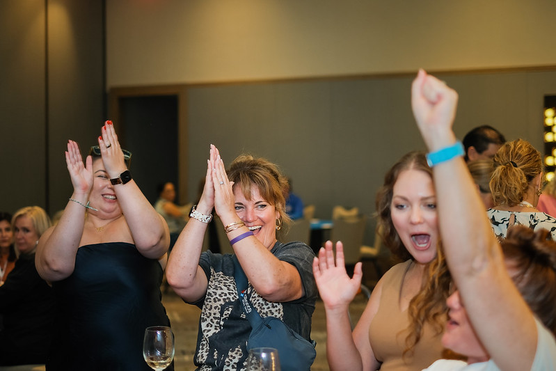Women cheering and clapping at a WGA Symposium event.