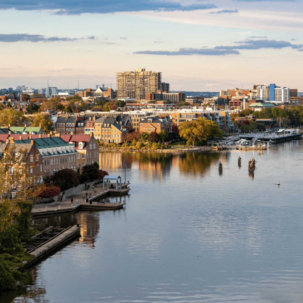 Cityscape of Alexandria waterfront with buildings, trees, and boats along the river.